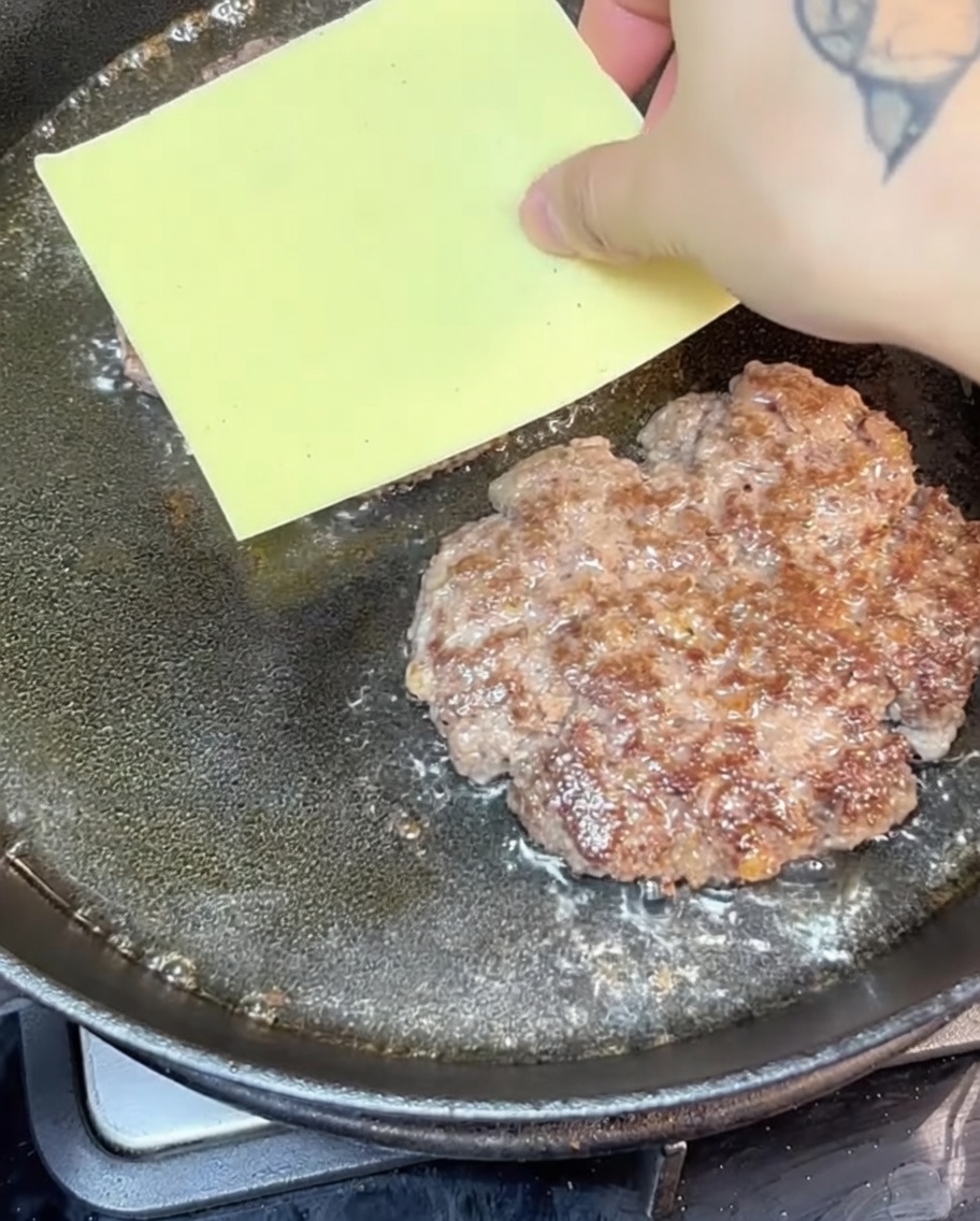 Steaks au fromage grésillant dans une poêle en fonte.
