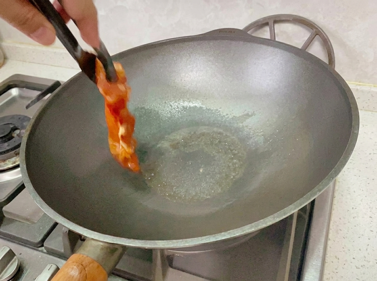 Poulet mariné en train de cuire dans une poêle à feu moyen-doux.
