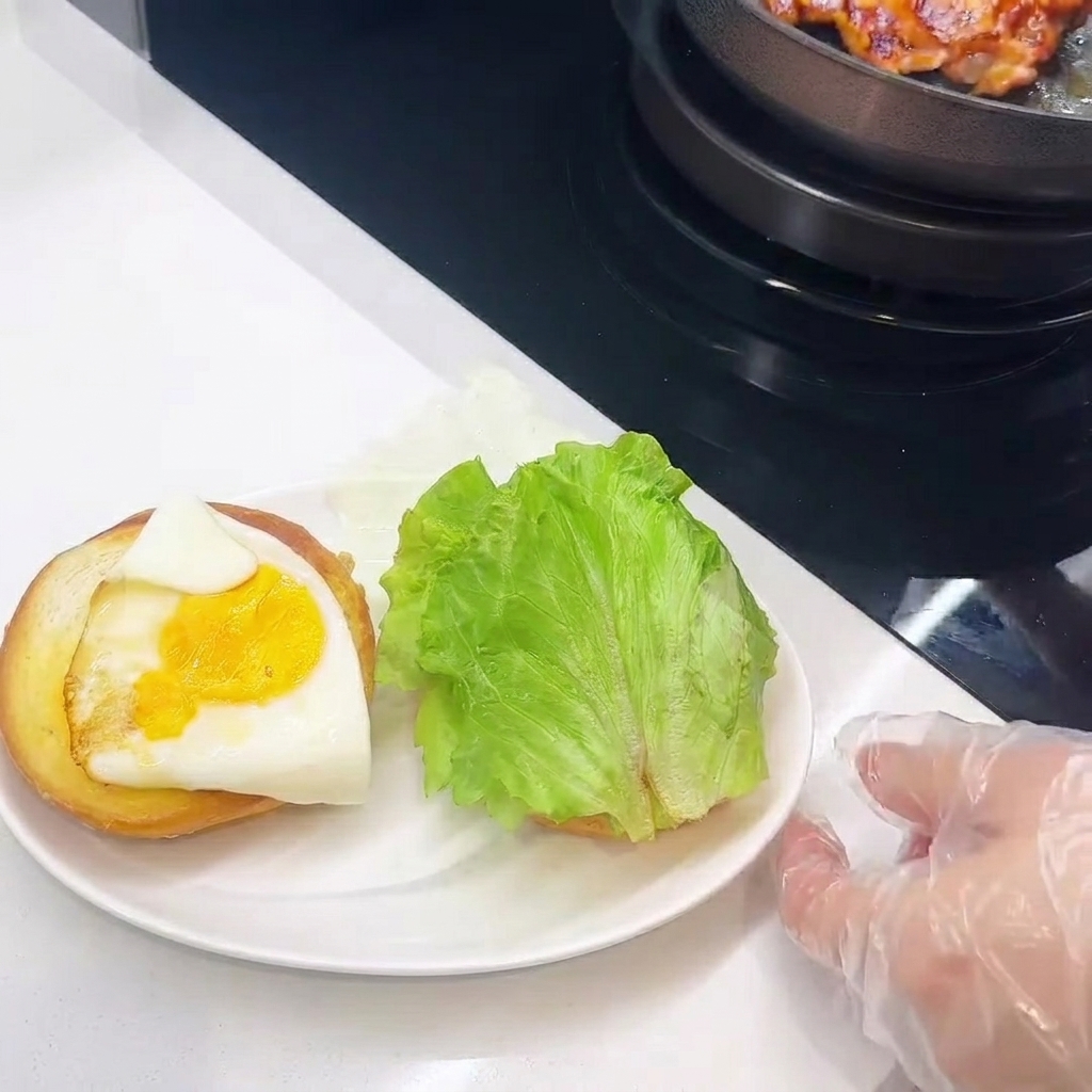Gros plan sur le montage du burger avec le poulet, le fromage, lœuf et la laitue.