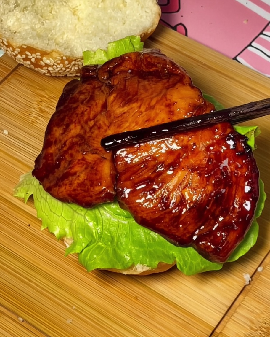 Poulet teriyaki, tomate et fromage empilés sur le pain à burger.