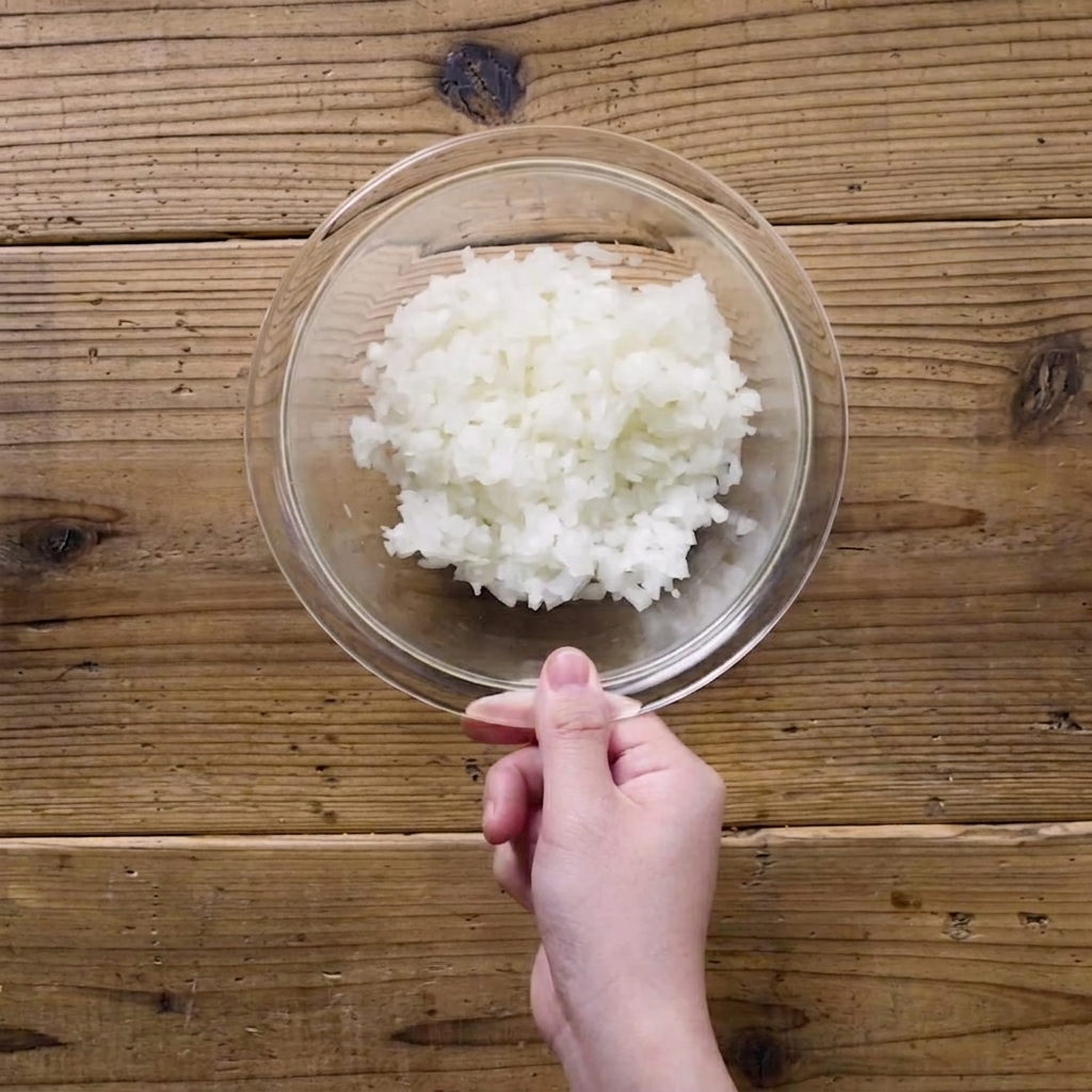 Oignons finement hachés dans un bol en verre transparent recouvert dun film plastique.