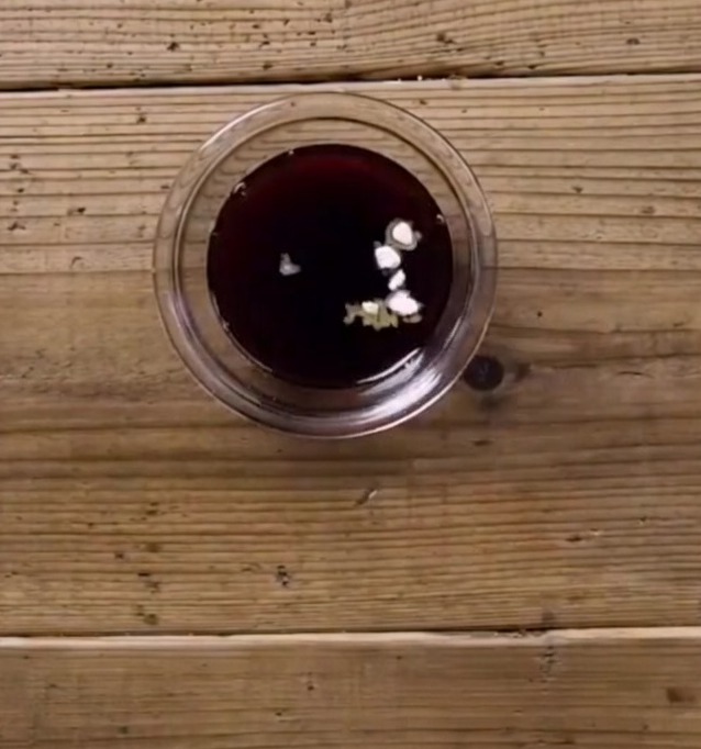 Mélange foncé pour sauce teriyaki avec des morceaux blancs de fécule et de sucre visibles dans un petit bol en verre sur une surface en bois.