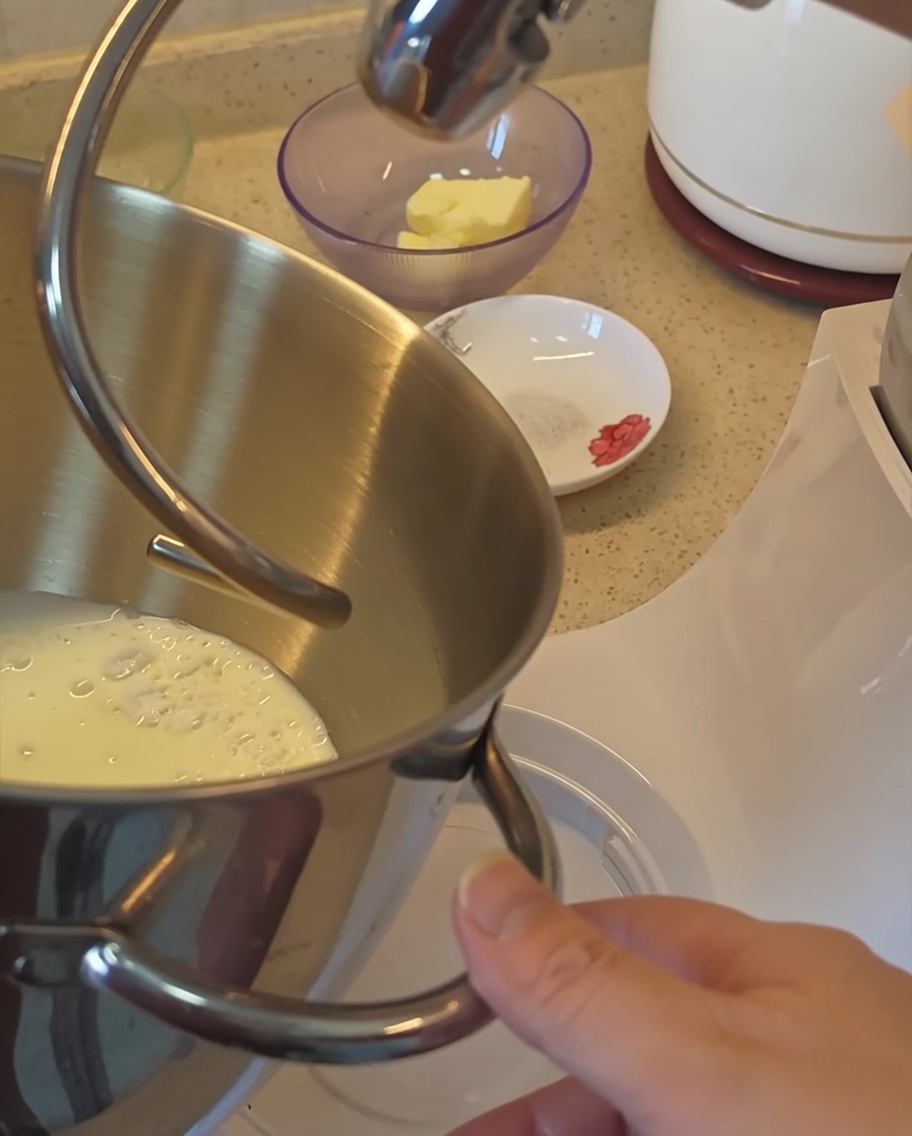 Vue rapprochée du bol du robot contenant les ingrédients secs et le lait pour la pâte à pain.