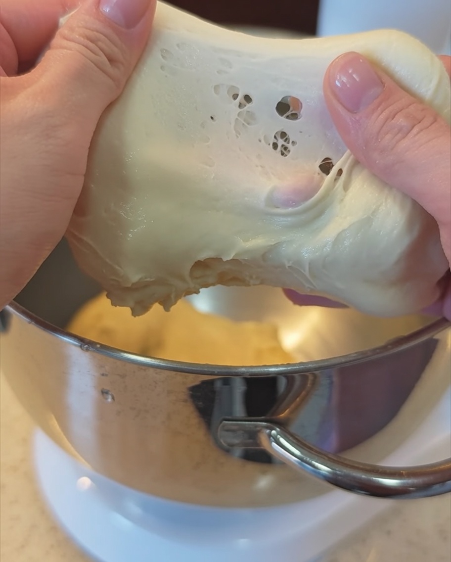 Mains étirant un morceau de pâte élastique pour vérifier le stade de la membrane.