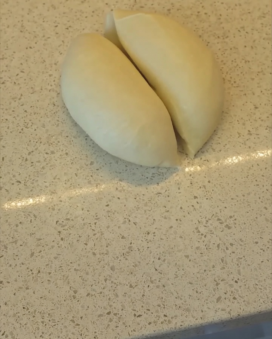 Un coupe-pâte divisant une boule de pâte en deux parts égales sur un plan de travail.