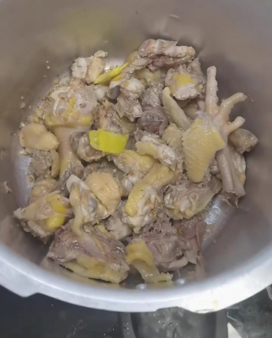 Eau versée dans lautocuiseur sur le poulet et les aromates.