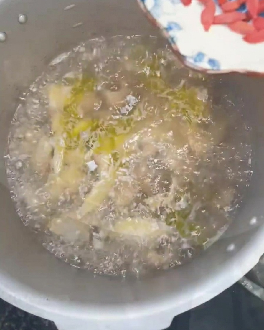 Baies de goji et ciboules fraîches hachées saupoudrées dans une soupe de poulet bouillante.