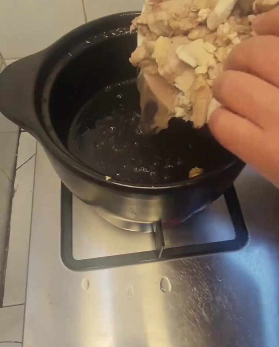 Morceaux de poulet blanchis déposés dans un pot en terre cuite préchauffé.