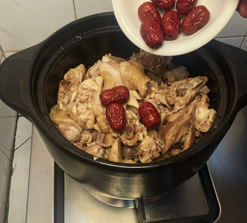 Dattes rouges séchées ajoutées dans le pot avec le poulet.