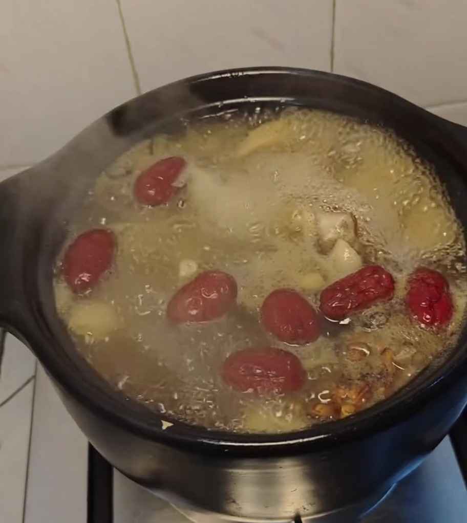 Soupe de poulet mijotant dans le pot en terre cuite.
