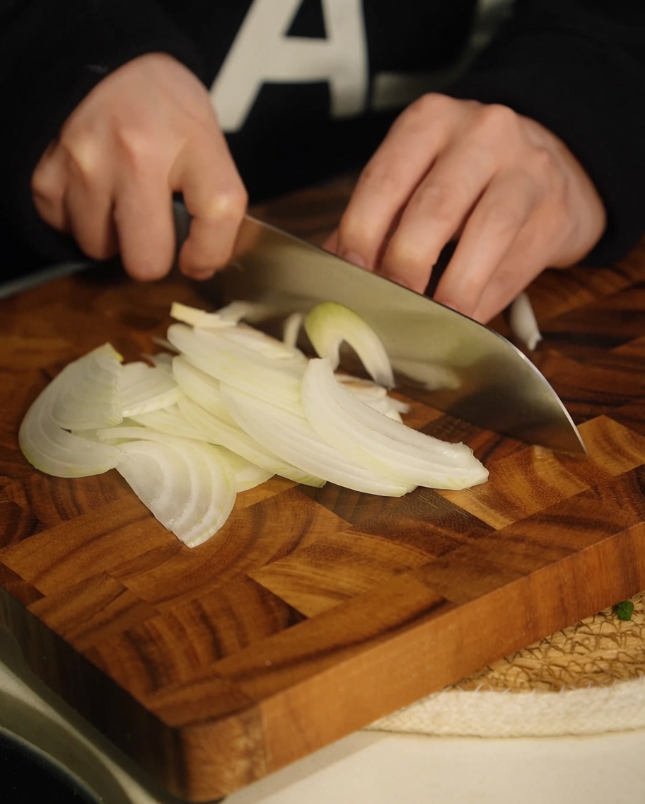 Lanières doignon blanc finement tranchées sur une planche à découper en bois.