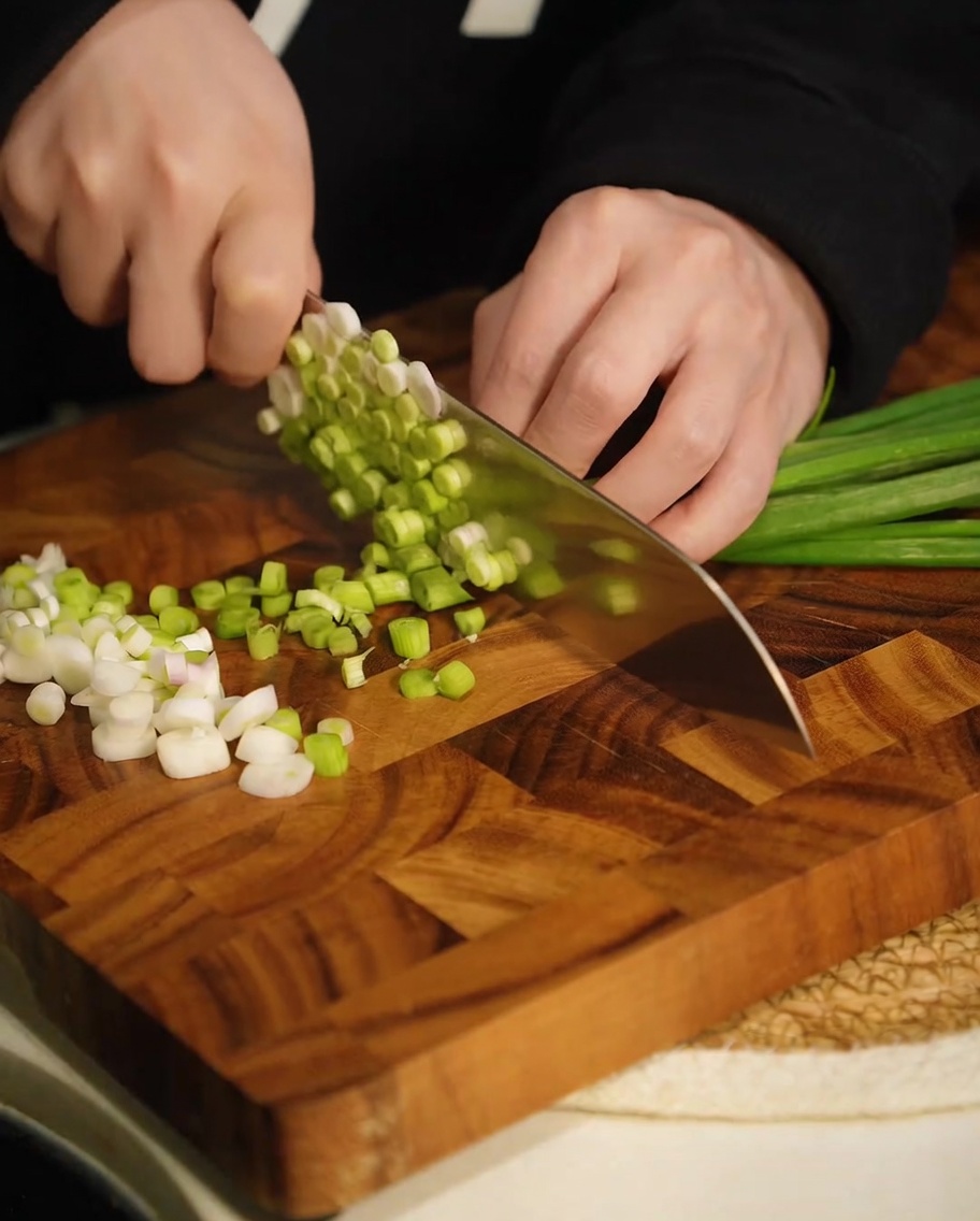 Oignons nouveaux verts fraîchement hachés sur une planche à découper.