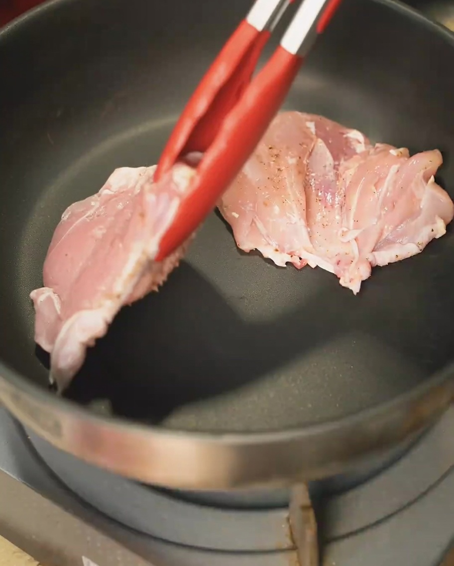 Cuisses de poulet saisies à la poêle, côté peau, obtenant une croûte dorée.