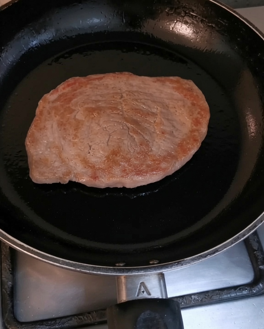 Un filet de bœuf en train de dorer dans une poêle noire brûlante.