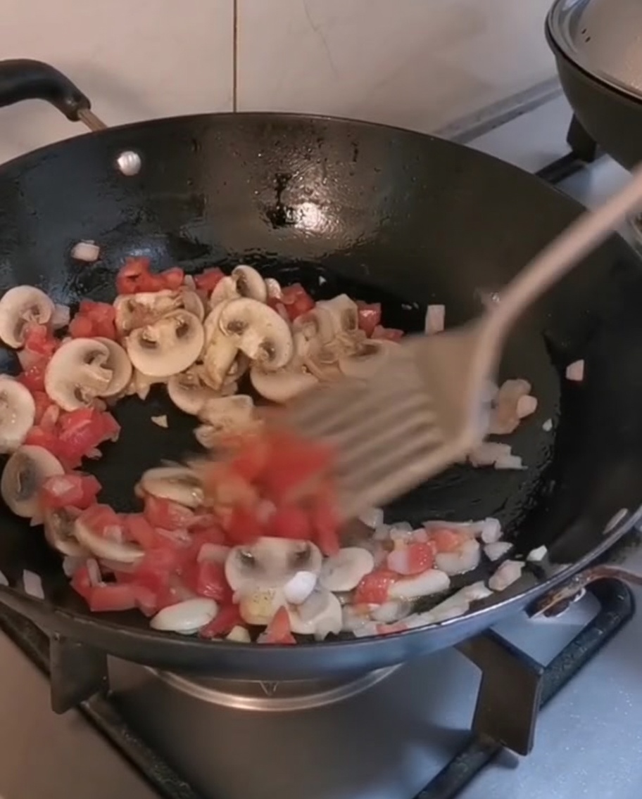 Mélange des pennes et des lanières de steak dans un wok avec les légumes sautés.