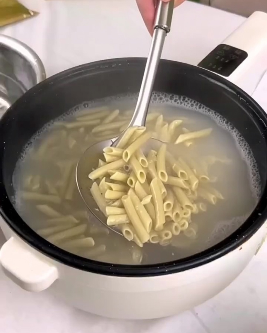 Pâtes cuites transférées dune casserole dans un bol deau froide à laide dune écumoire.