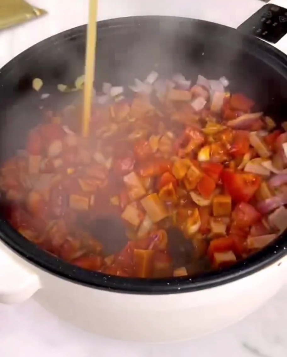 Sauce tomate versée dans la poêle contenant les légumes et le jambon.