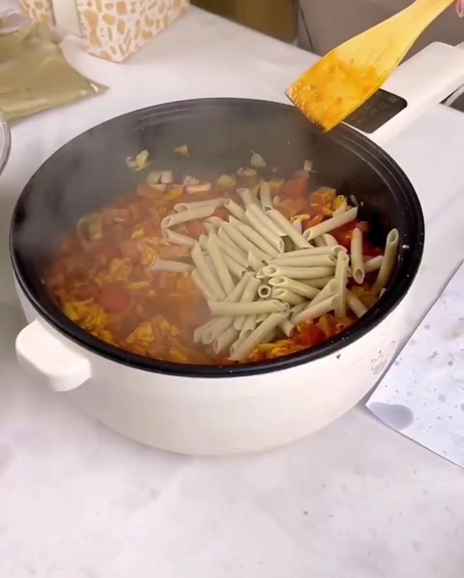 Penne cuites ajoutées à la poêle avec la sauce et la garniture.