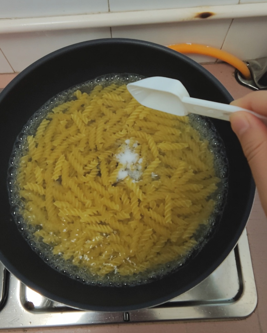 Ajout dune cuillerée de sel dans leau des pâtes.