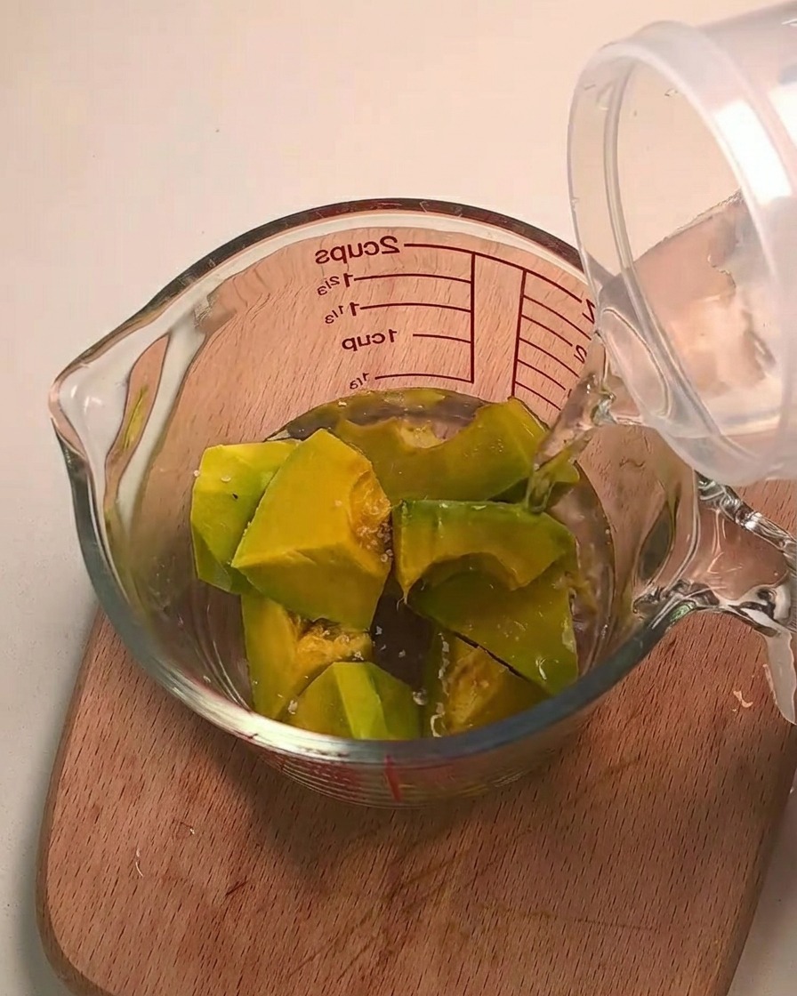De leau versée sur des morceaux de courge kabocha dans une tasse à mesurer en verre.