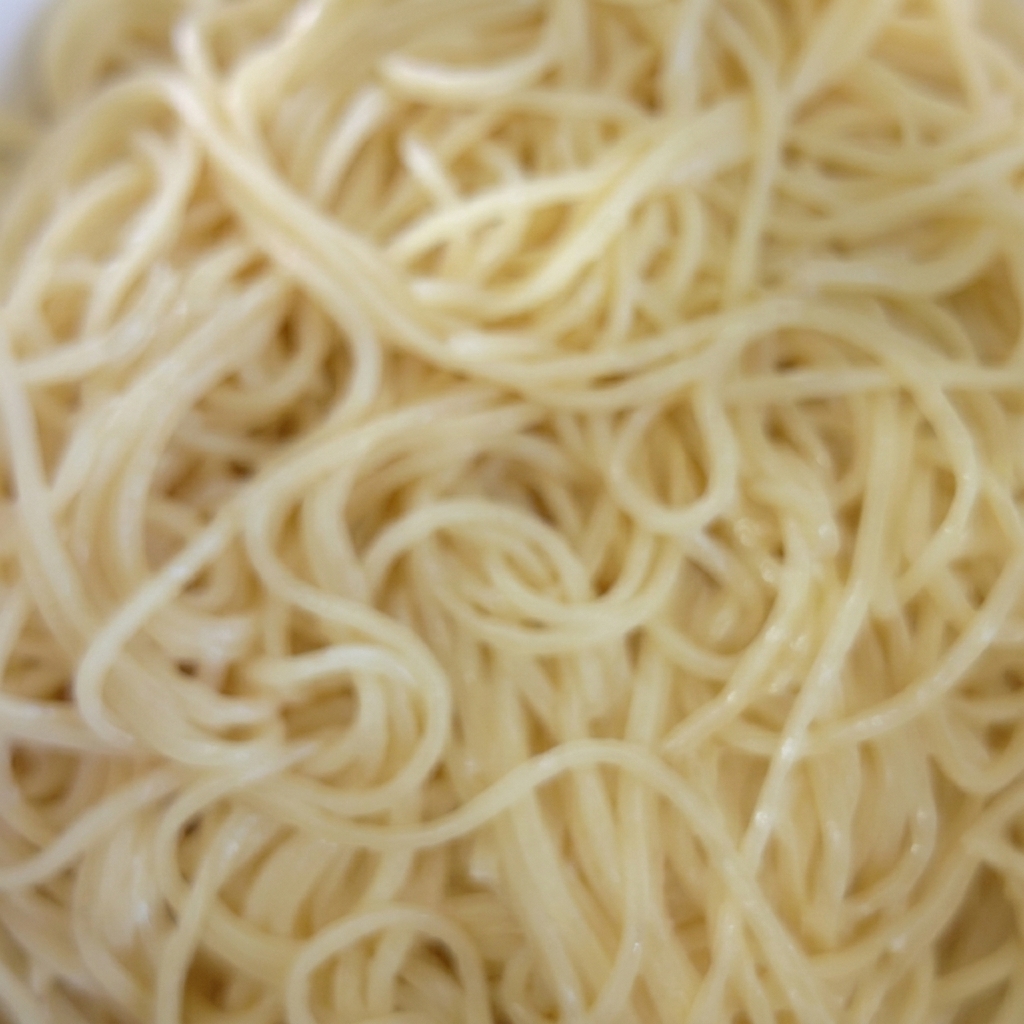 Un bol de spaghettis cuits en train dêtre mélangés avec de lhuile.