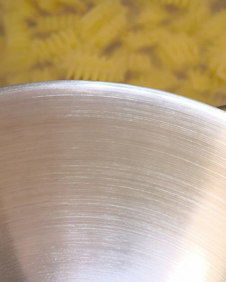 Eau de cuisson chaude versée dans le bol de mélange, interagissant avec le beurre et les assaisonnements.
