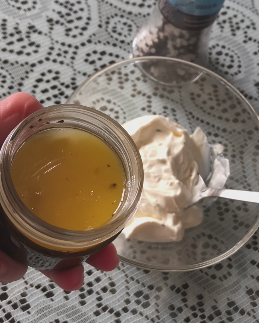 Une cuillère de sauce à la truffe noire ajoutée dans un bol de crème fraîche.