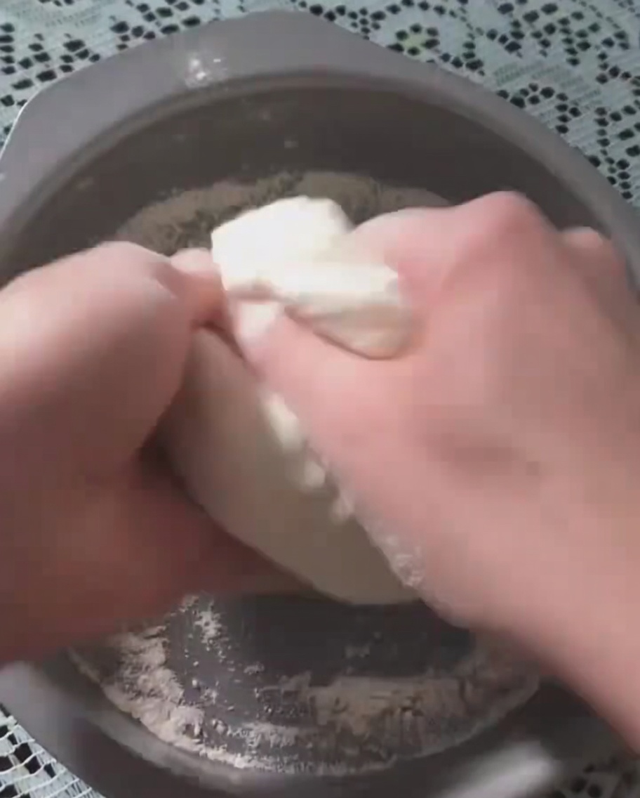 Mains pressant une pâte à pizza fermentée dans un moule rond en métal.