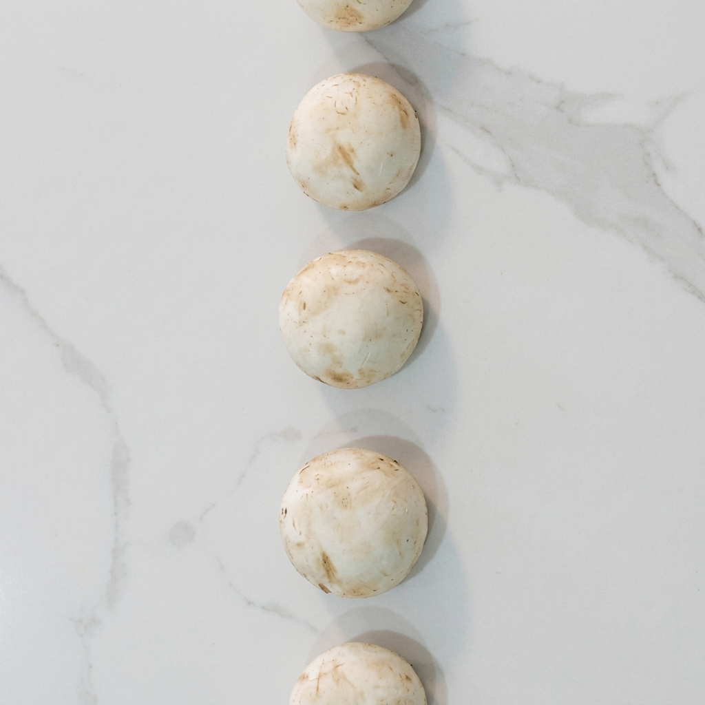 Tranches de champignons blancs sautées dans une poêle avec de la crème jusquà ce quelles soient tendres et dorées.