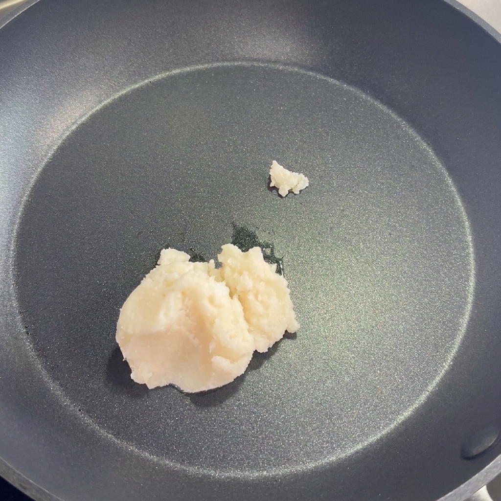 Une poêle contenant du saindoux fondu, de lhuile végétale, des oignons et des poireaux en train de frire.