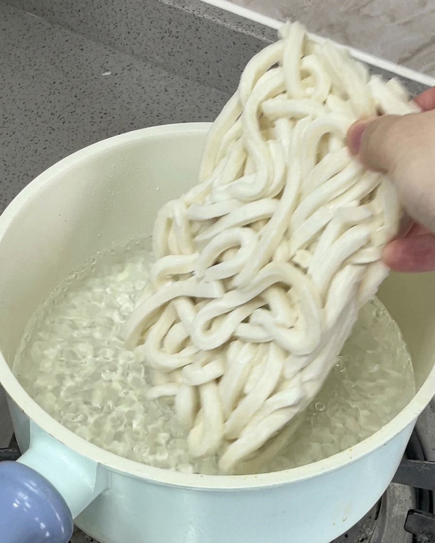 Nouilles udon plongées dans une casserole deau bouillante.