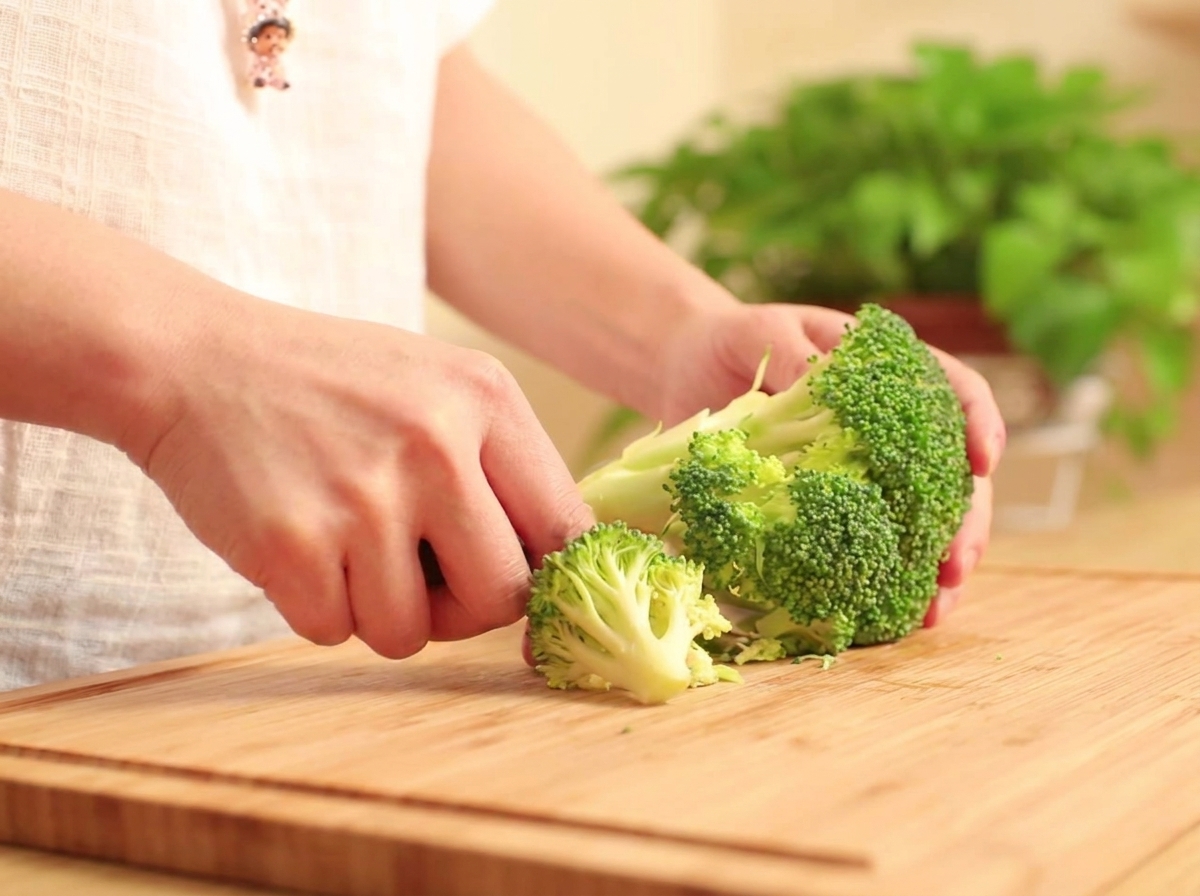 Têtes de brocoli frais séparées sur une planche à découper en bois.