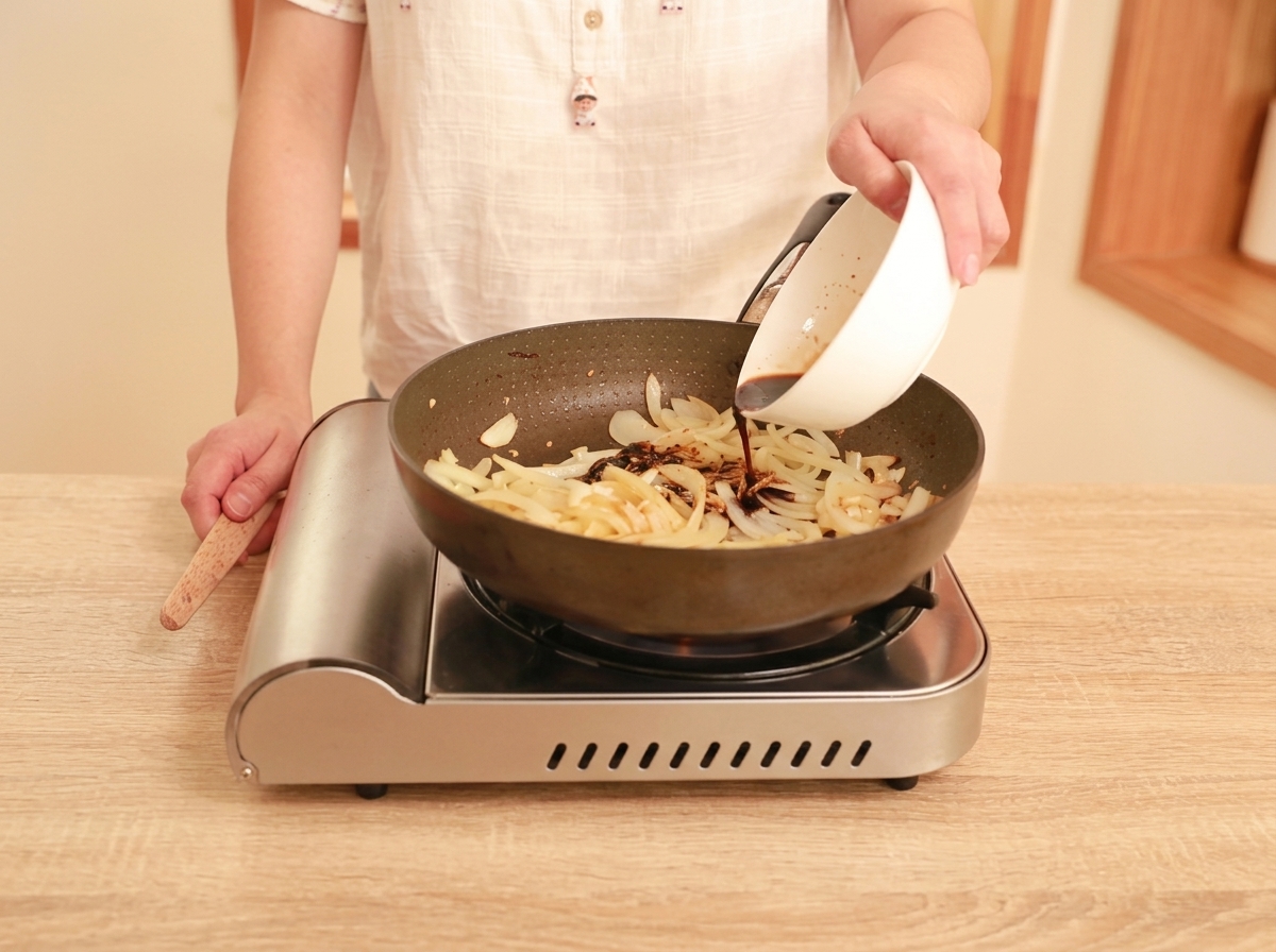 Sauce brune foncée versée dun bol blanc dans une poêle contenant les oignons, le gingembre et lail sautés.