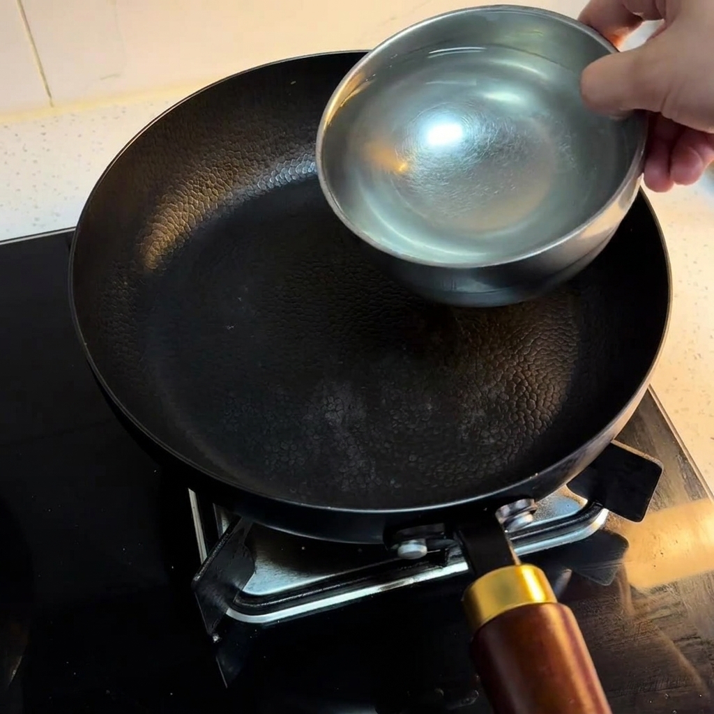 Trois bols deau versés dans une poêle noire sur une plaque de cuisson.