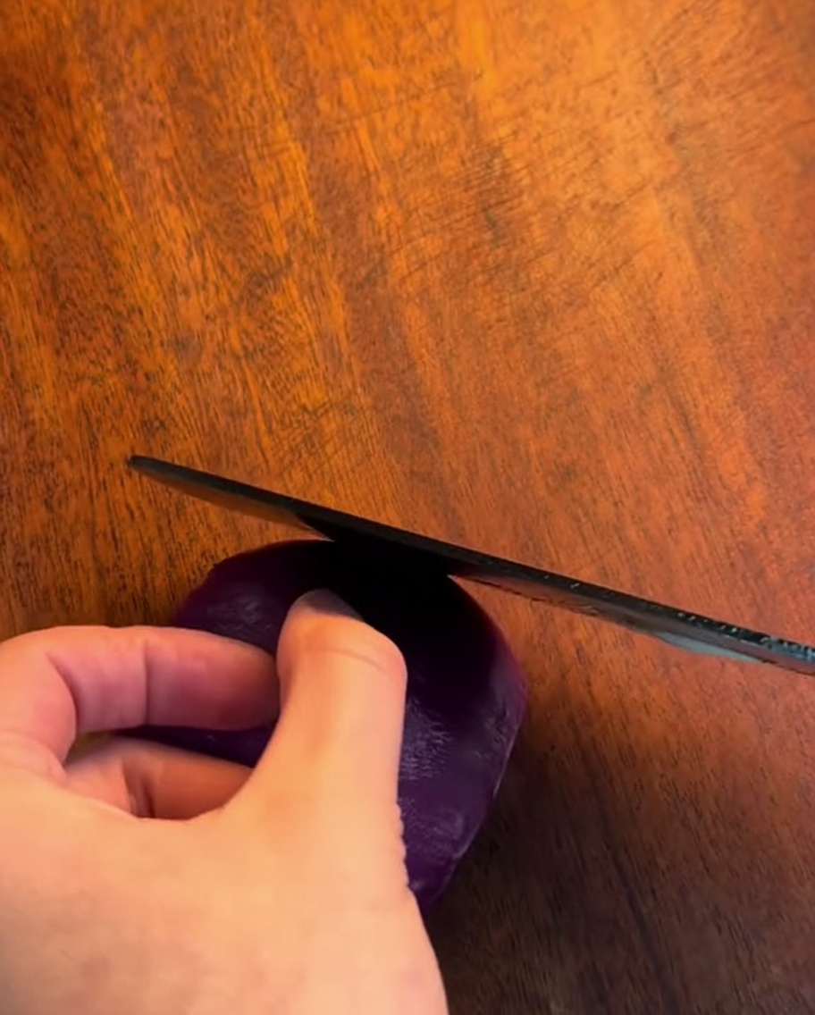 Un couteau aiguisé éminçant un oignon en fines lamelles sur une planche en bois.