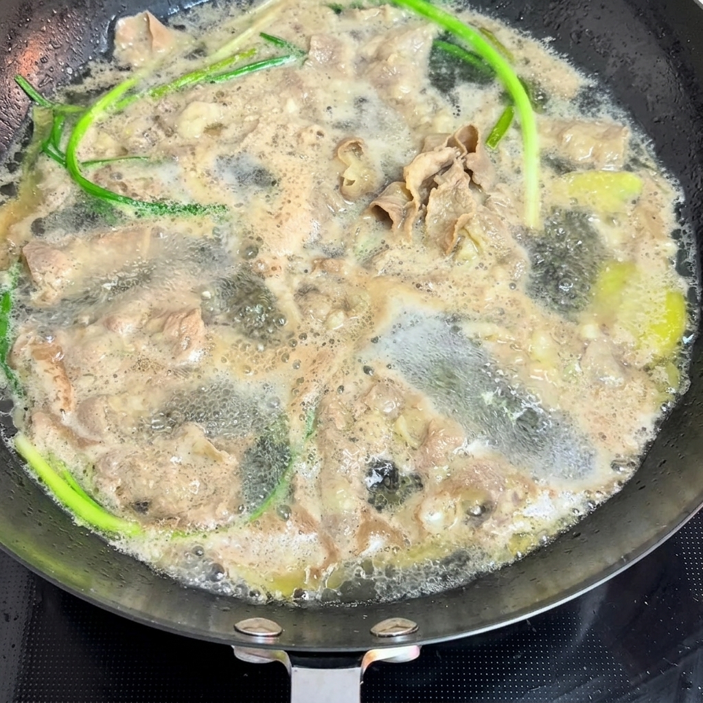 Fines tranches de bœuf et oignons verts blanchis dans une casserole deau bouillante.