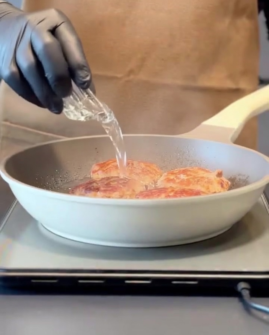 De leau versée dans une poêle chaude contenant des steaks saisis, créant de la vapeur avant de couvrir avec un couvercle.
