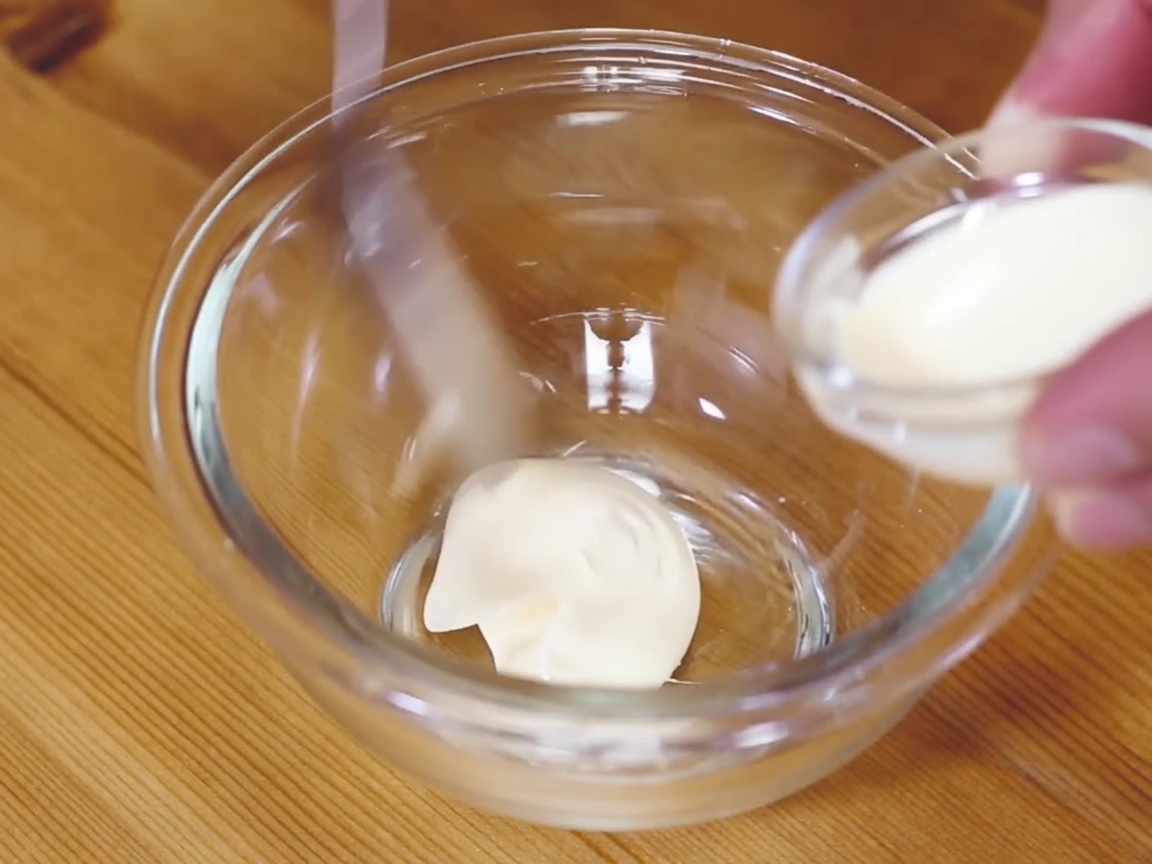 Un petit bol de mayonnaise au wasabi mélangée à la cuillère.