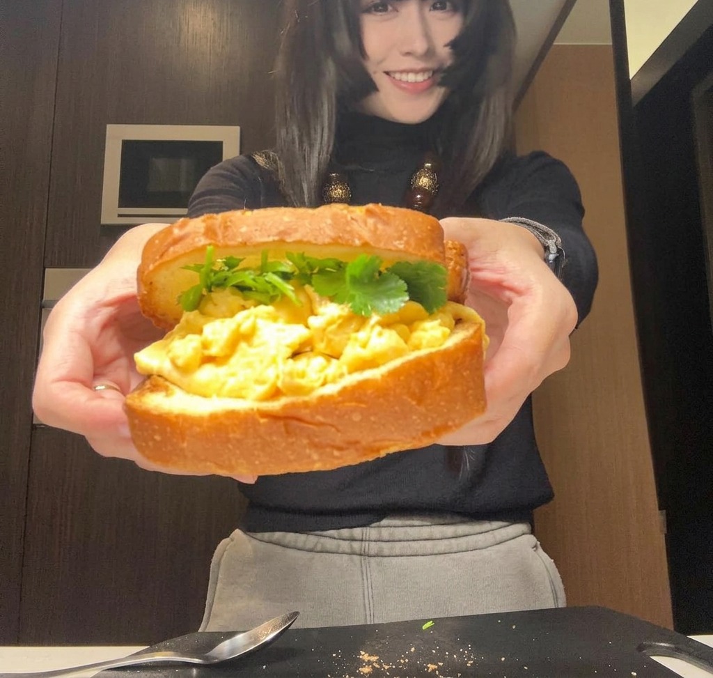 Un sandwich complètement assemblé, tenu à deux mains, prêt à être emballé.