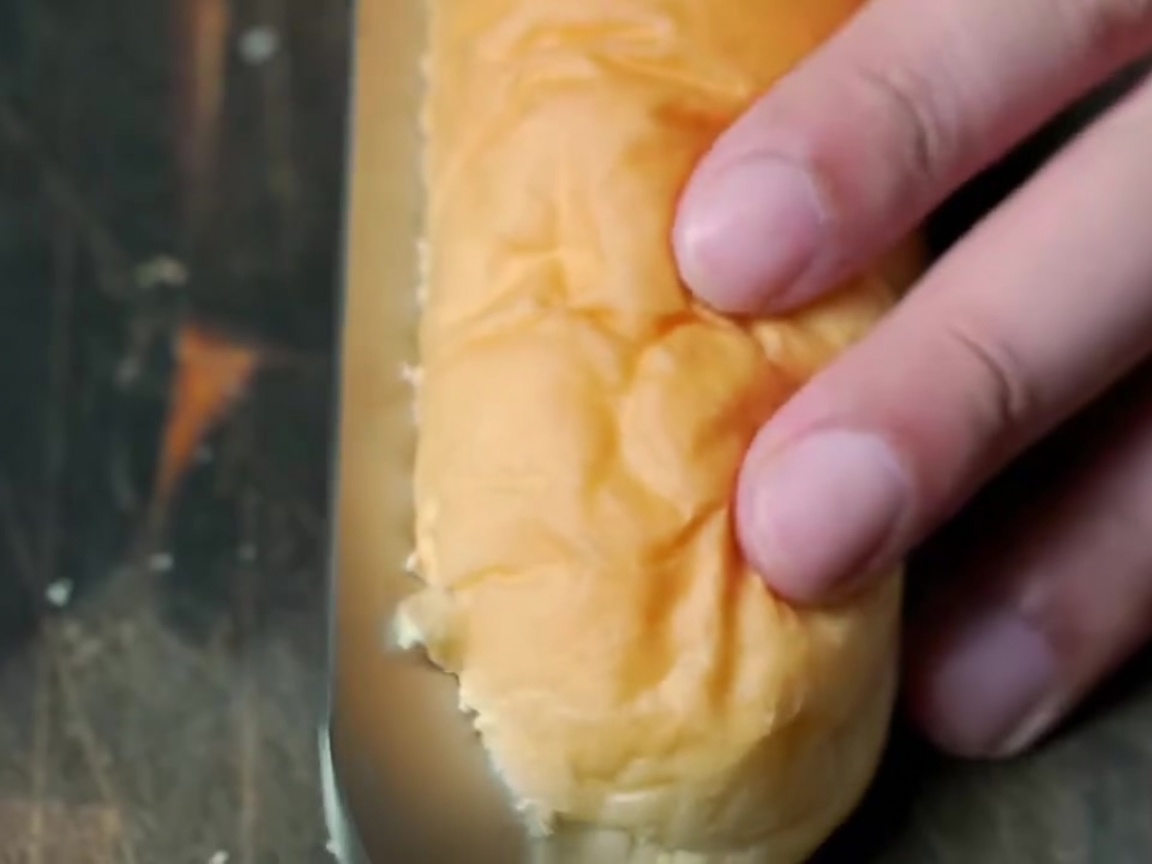 Gros plan dun pain long ouvert en deux avec un couteau de cuisine.