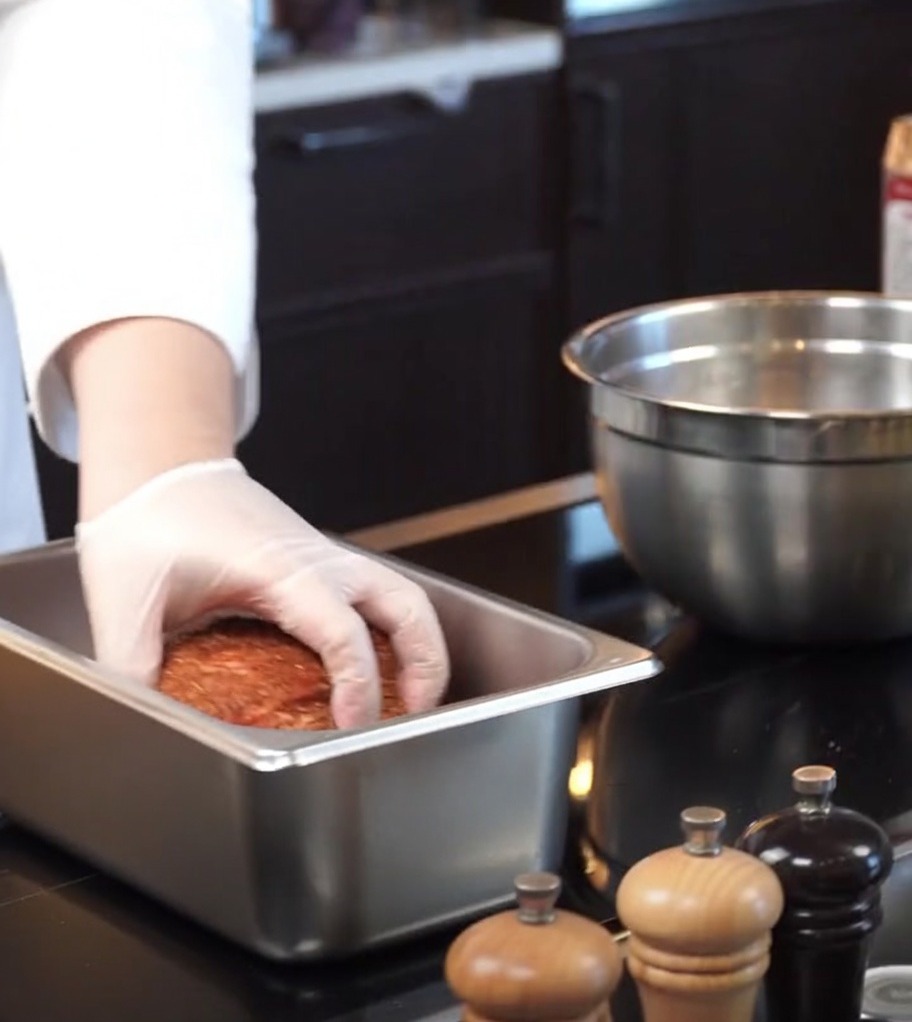 Le porc assaisonné déposé dans un plat de cuisson rectangulaire en inox.