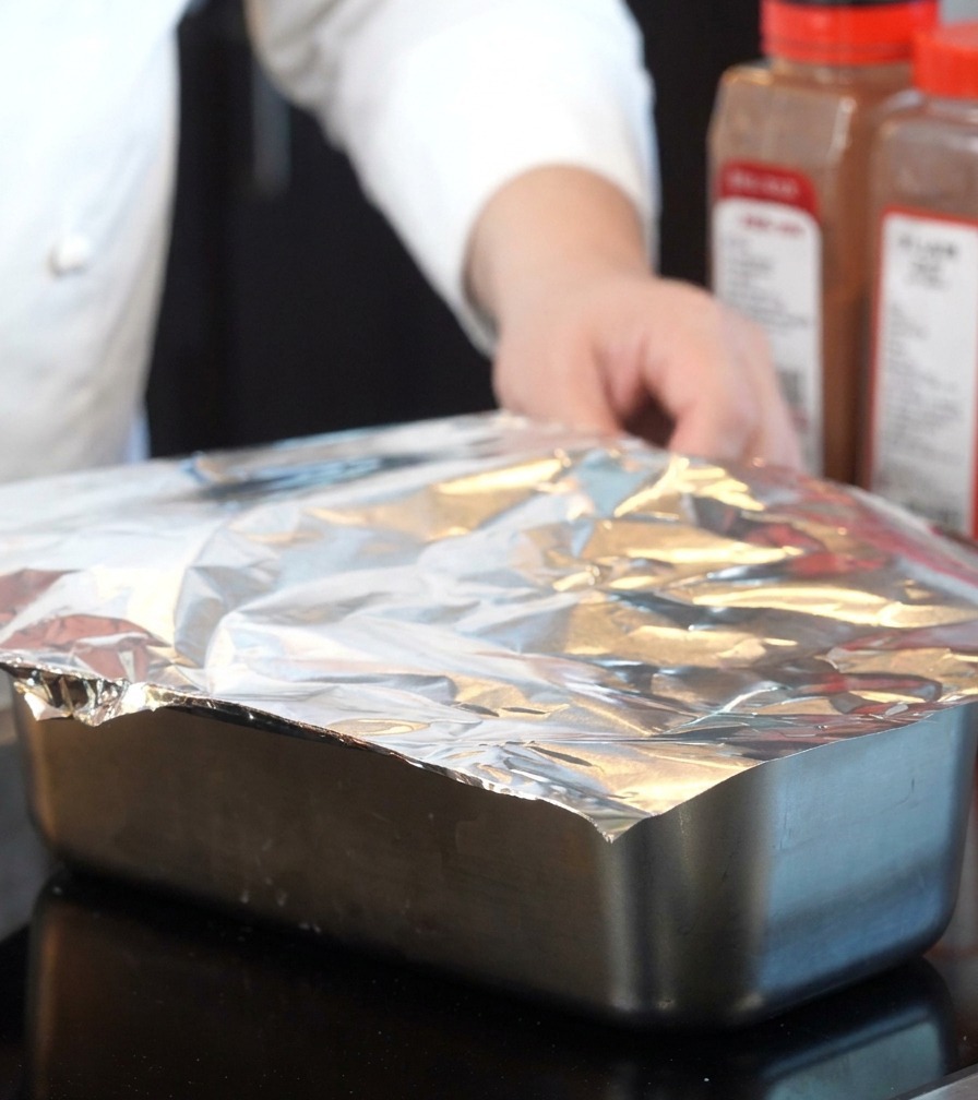 Du papier aluminium utilisé pour couvrir hermétiquement un plat de cuisson métallique.