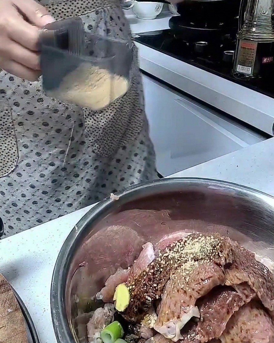 Des ingrédients mélangés avec des tranches de porc cru dans un bol en acier inoxydable.