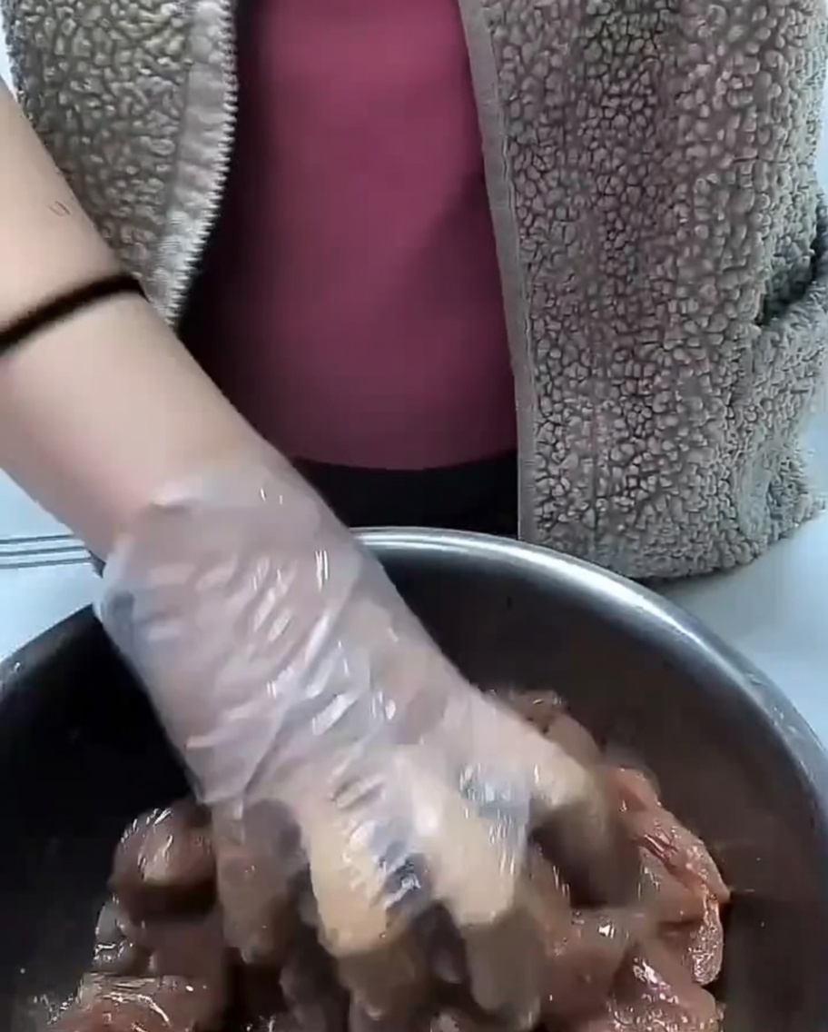 De lhuile de cuisson versée sur les morceaux de porc assaisonnés dans un bol en métal.