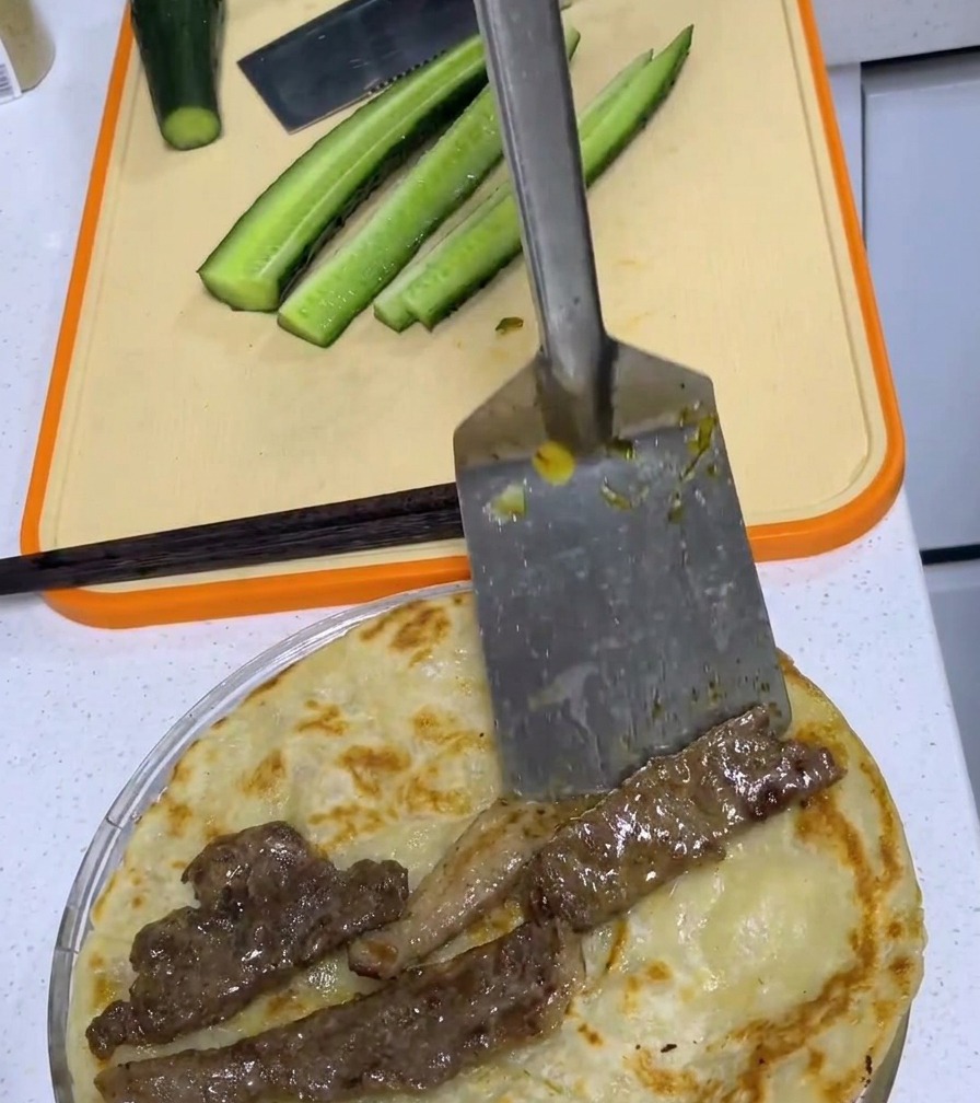 Une côte de porc cuite centrée sur un pancake à loignon doré sur une planche à découper.