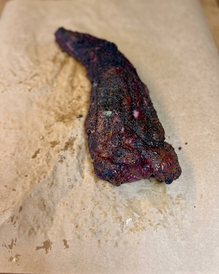 Un travers de bœuf fumé roulé serré dans du papier de boucher pour former un paquet hermétique.