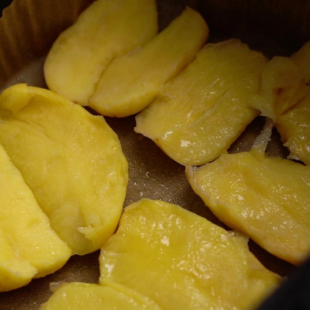 Pommes de terre dans le panier de lair fryer enrobées dhuile, assaisonnées de gros sel et de graines de sésame.