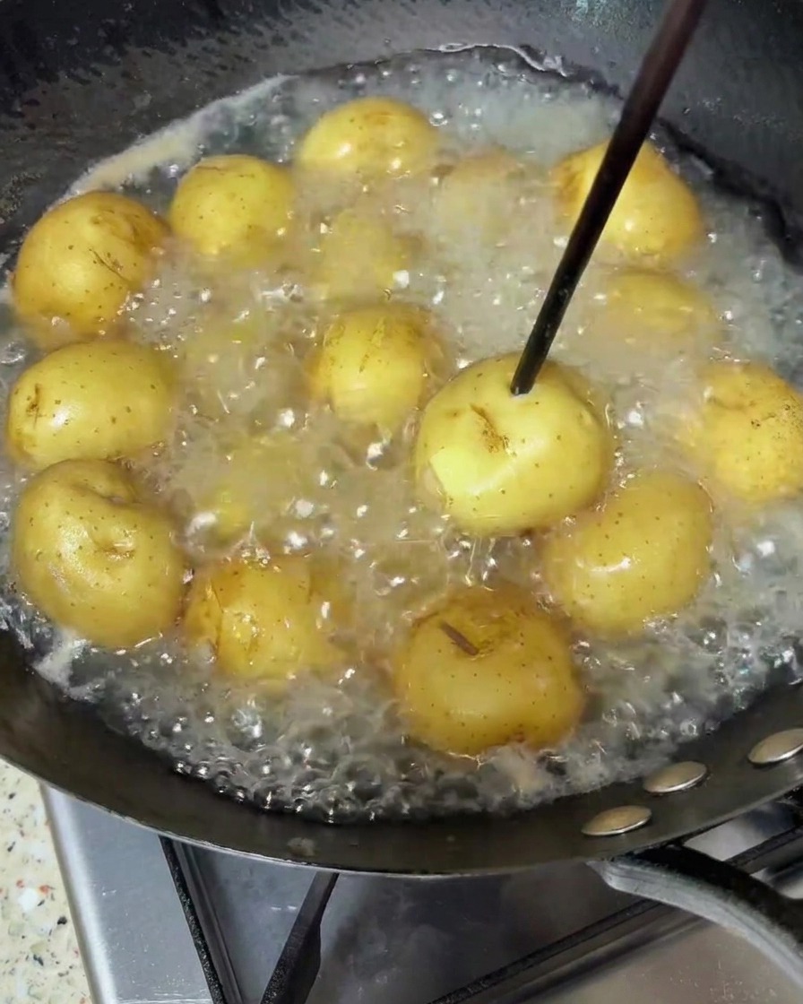 Petites pommes de terre frémissant dans de leau bouillante, piquées avec une baguette en bois pour vérifier la cuisson.