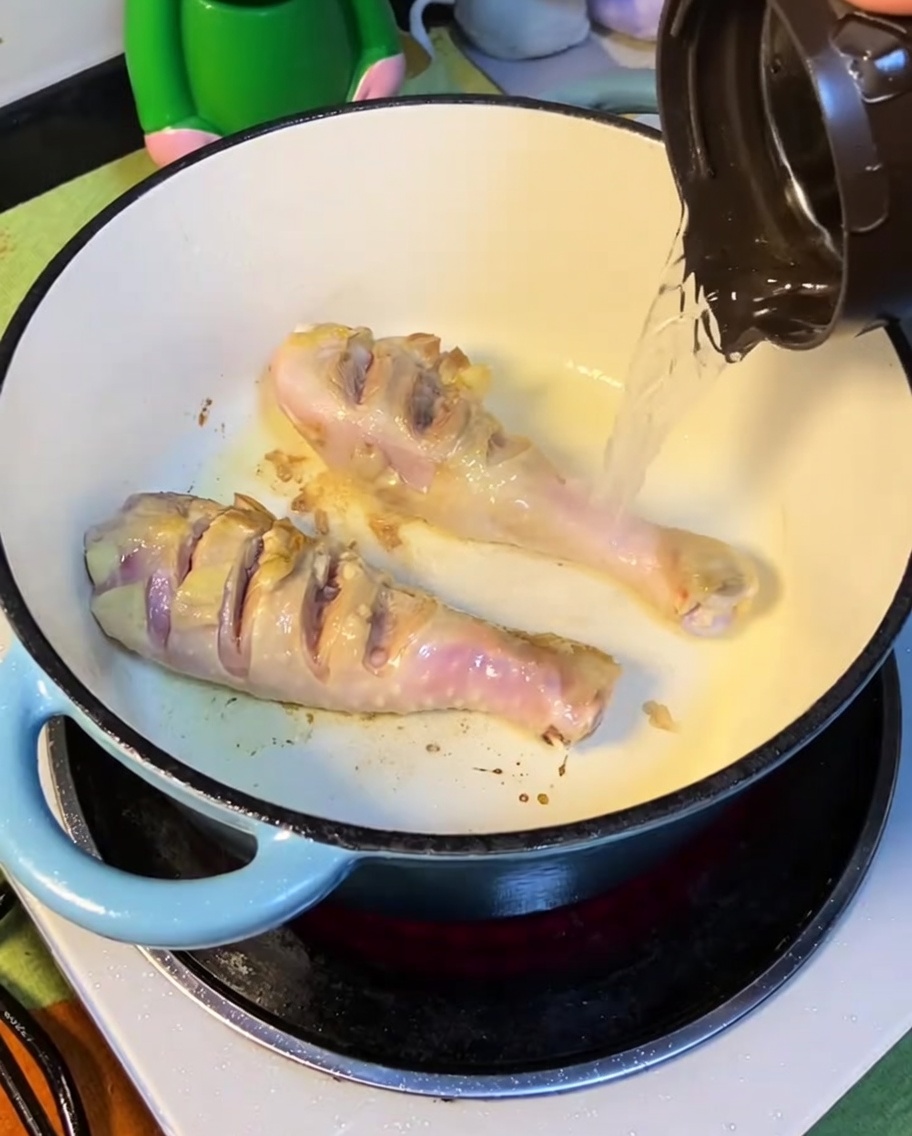 Eau bouillante versée dans la marmite contenant le poulet saisi.