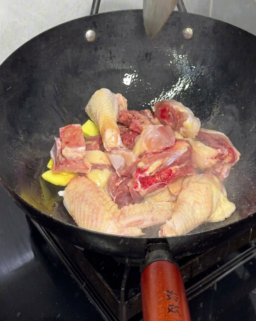Morceaux de poulet frais saisis au wok avec des tranches de gingembre.